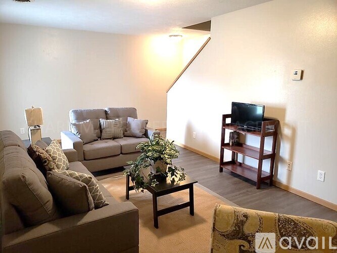 A living room with a couch, chair, and television.