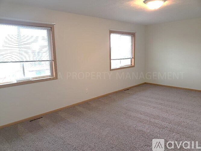 A room with a carpeted floor and two windows.