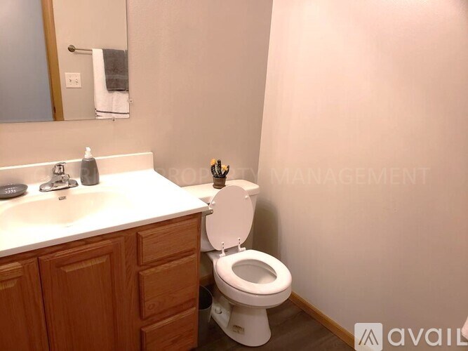 A white toilet in a bathroom with a wooden cabinet and a mirror above it.