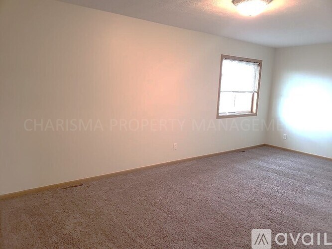 A room with a window and carpeted floor.