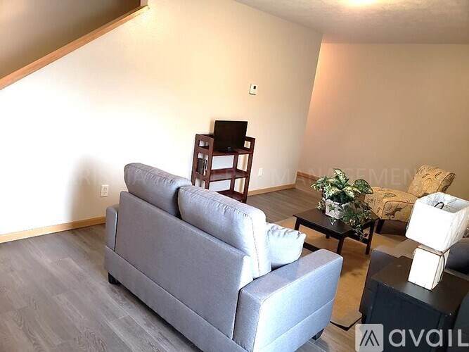 A living room with a grey couch, a black chair, and a coffee table with a plant on it.