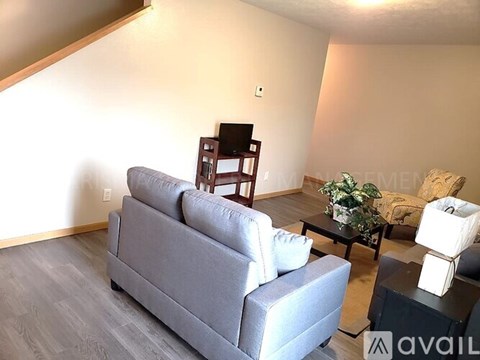 A living room with a grey couch, a black chair, and a coffee table with a plant on it.