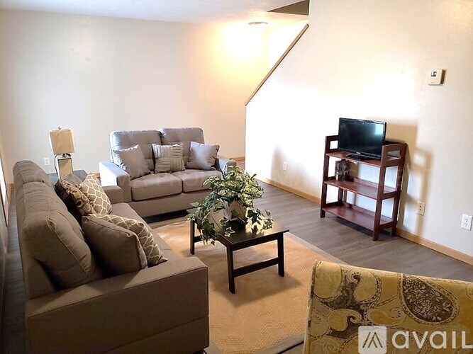 A living room with a couch, a chair, a coffee table, and a television.
