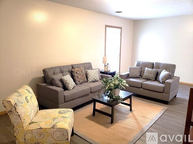 A living room with two grey couches, a coffee table, and a yellow patterned armchair.