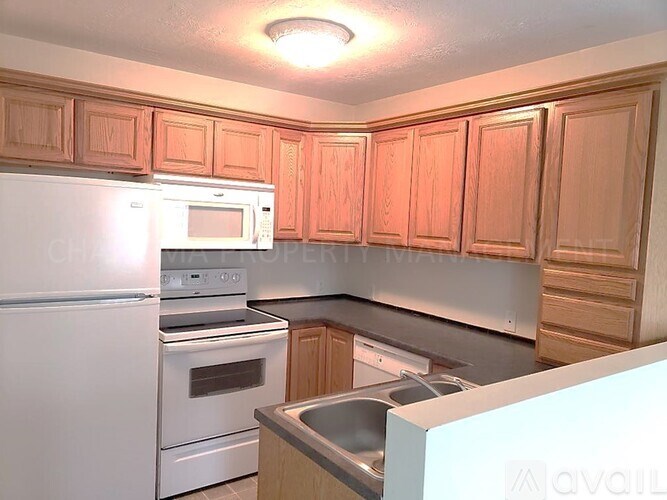 A kitchen with wooden cabinets and white appliances.
