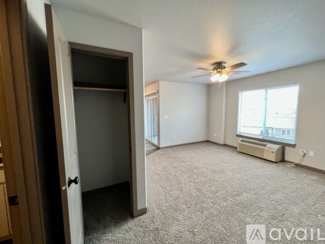 A spacious room with a ceiling fan and a window with blinds.