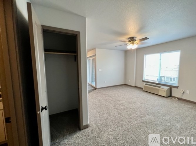 A spacious room with a ceiling fan and a window with blinds.