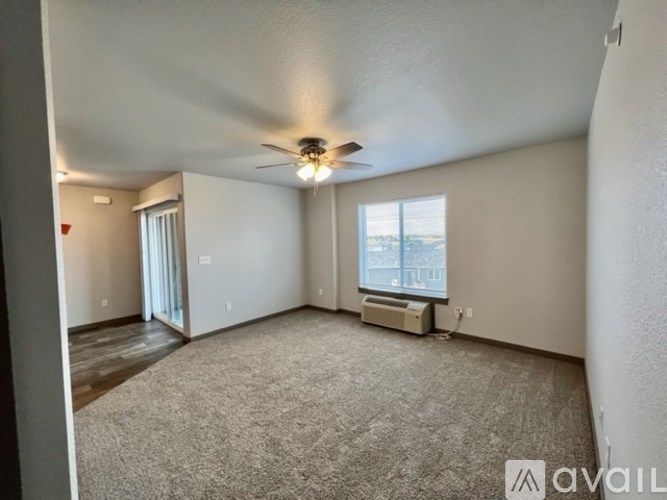 A spacious room with a carpeted floor and a ceiling fan.