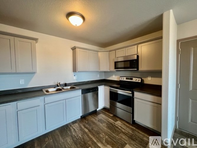 A kitchen with white cabinets and a black countertop.