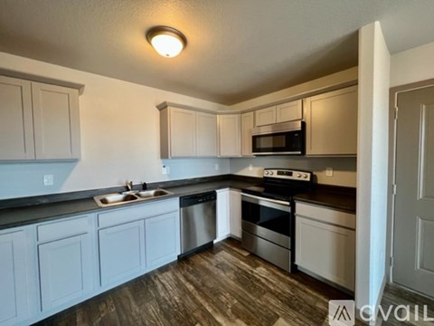 A kitchen with white cabinets and a black countertop.