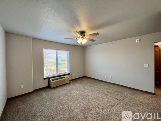 A room with a ceiling fan and a window with a view of the outside.