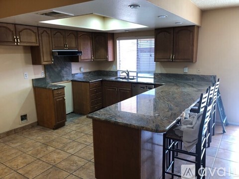 A kitchen with brown cabinets and a granite countertop.