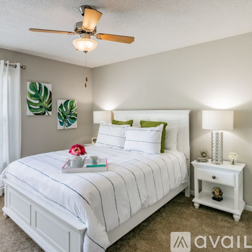 A bedroom with a white bed and a ceiling fan.