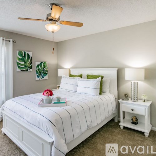 A bedroom with a white bed and a ceiling fan.