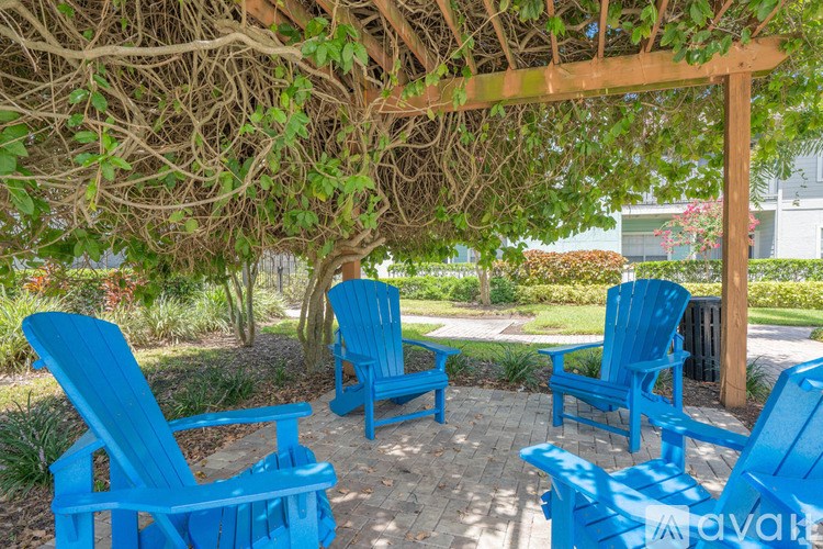 A set of blue chairs are arranged under a wooden pergola.