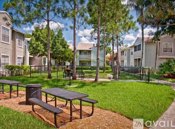 A park area with picnic tables and benches in front of apartment buildings.