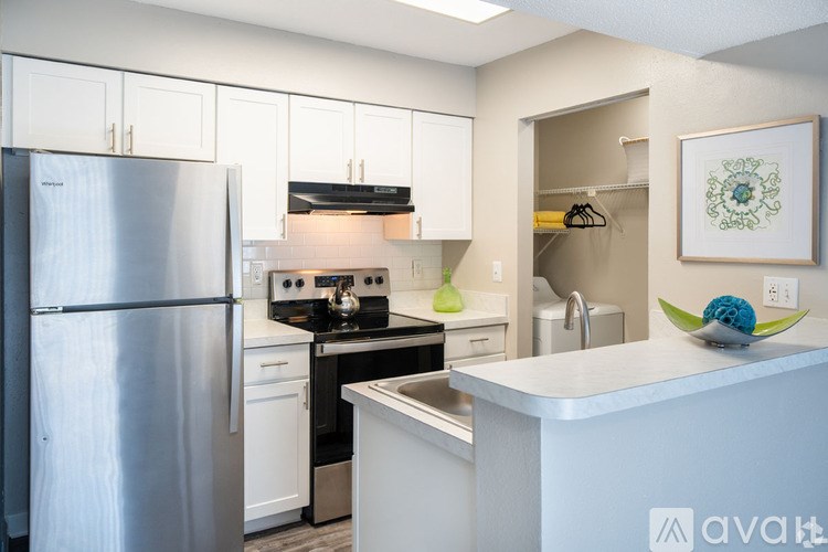A modern kitchen with a stainless steel refrigerator and white cabinets.
