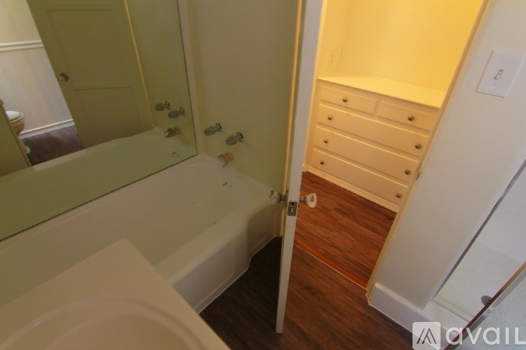 A bathroom with a tub and a wooden floor.