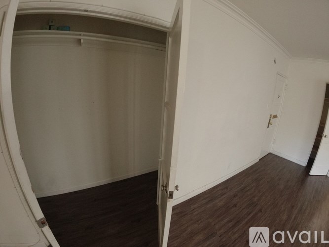 A room with a wooden floor and white walls, with a door on the right side.