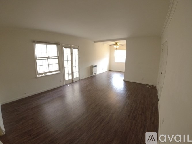 A room with wooden floors and two windows.