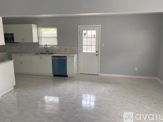 A kitchen with white cabinets and a blue trash can.