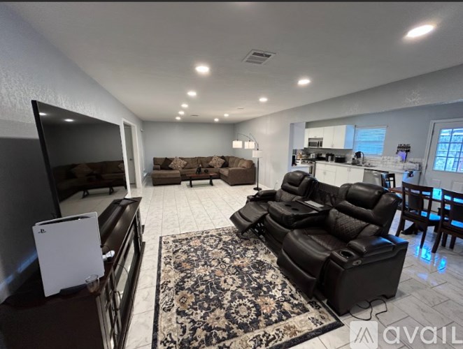 A living room with a black leather sofa and a rug.