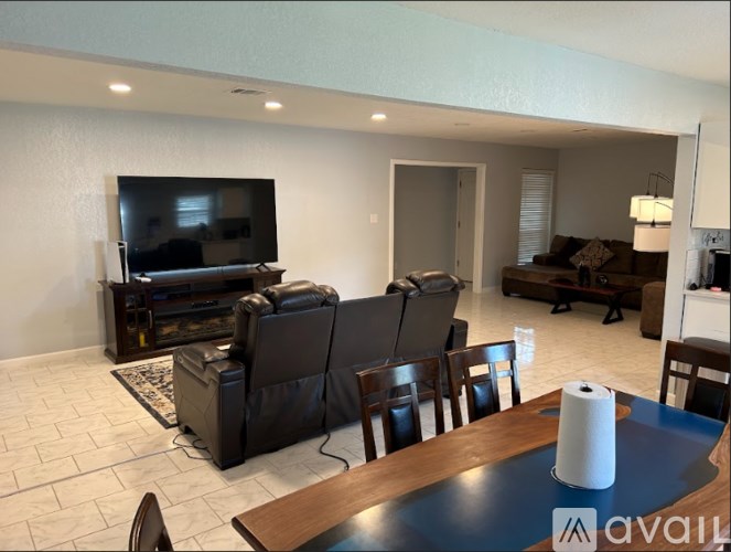 A living room with a television, couches, and chairs.