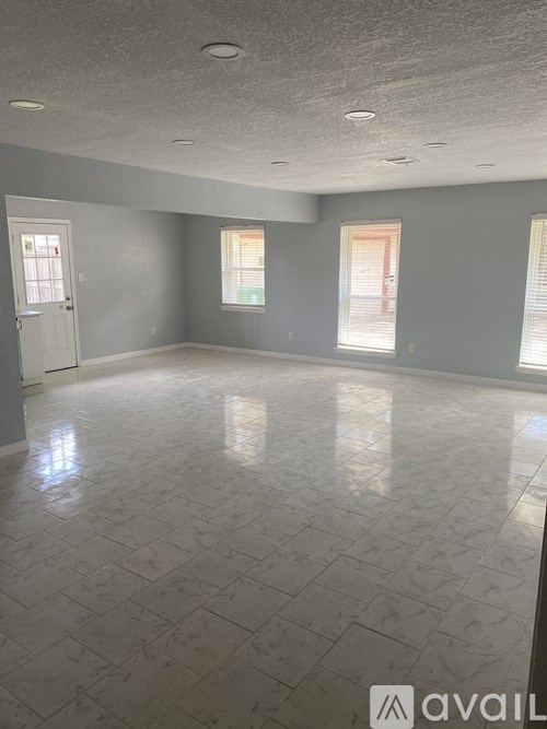 A spacious room with a marble floor and light grey walls.