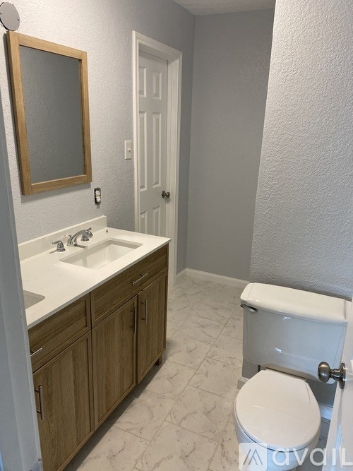 A white toilet sits in a bathroom next to a sink and a mirror.