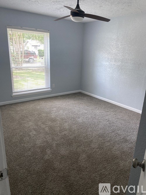 A room with a ceiling fan and carpeted floor.