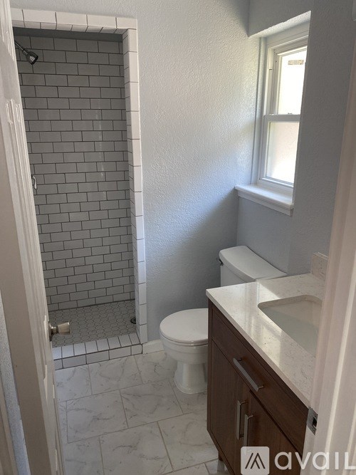 A bathroom with a toilet, sink, and tiled shower.