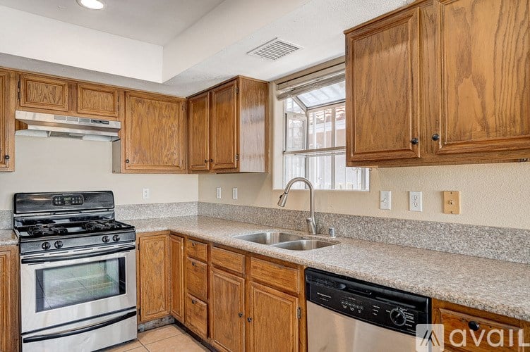A kitchen with wooden cabinets and a stainless steel dishwasher.