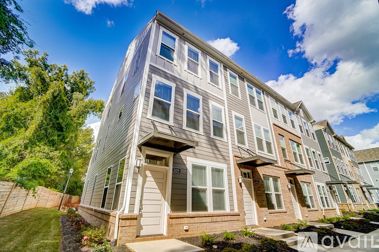A multi-story residential building with a front yard and a fence.