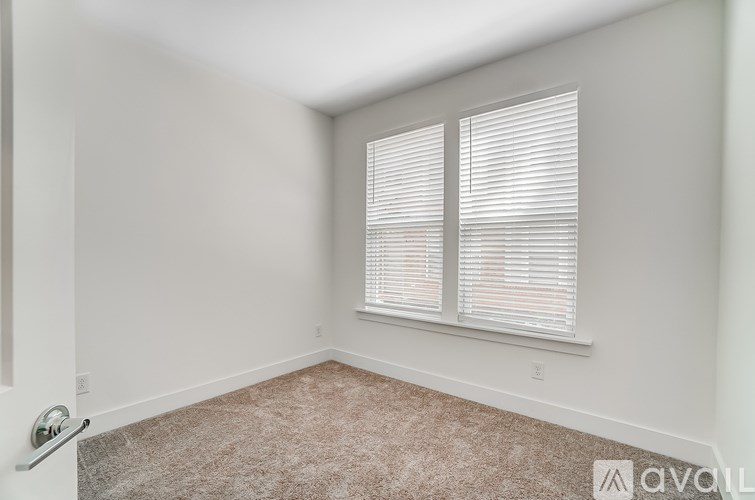 A room with a carpeted floor and a window with blinds.