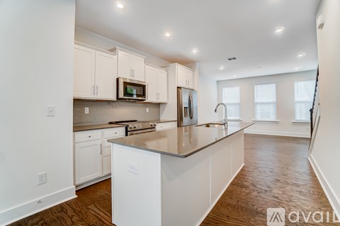 A kitchen with white cabinets and a wooden floor.