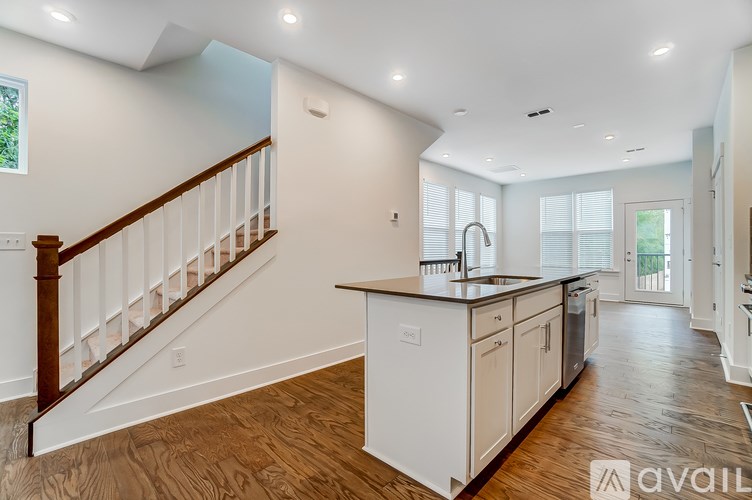 A spacious kitchen with white cabinets and a wooden staircase.