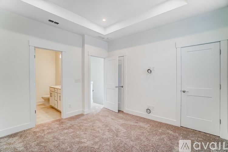 A room with white walls and a carpeted floor with a door on the right.