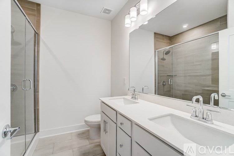 A bathroom with a white sink, toilet, and a walk-in shower.