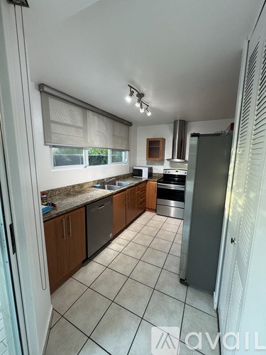 A kitchen with a refrigerator, sink, and stove.