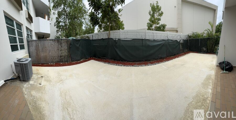 A backyard with a fence and a pool covered in a tarp.