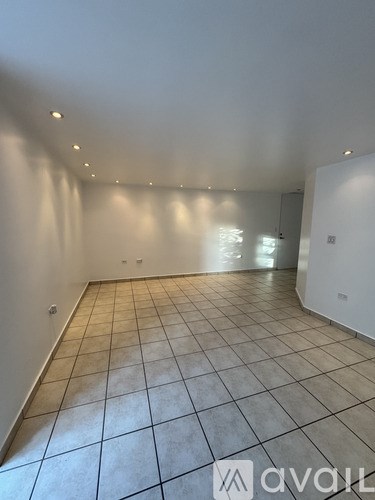 A spacious room with tiled flooring and recessed lighting.