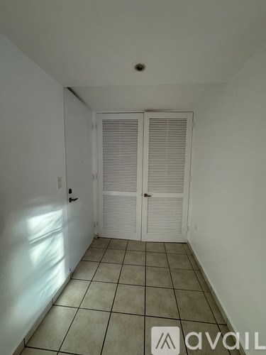 A room with white walls, a tiled floor, and a closed white door.
