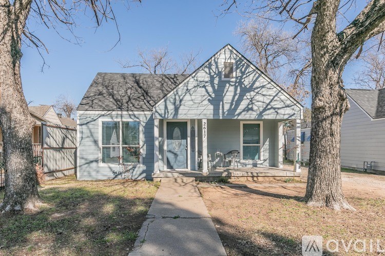 A house with a front yard and a tree in front of it.