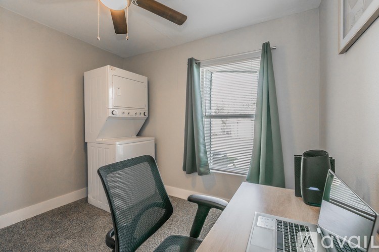A room with a desk, chair, and a window with a view of a building outside.