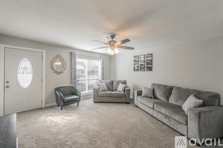 A living room with a grey couch, a black chair, and a white door.