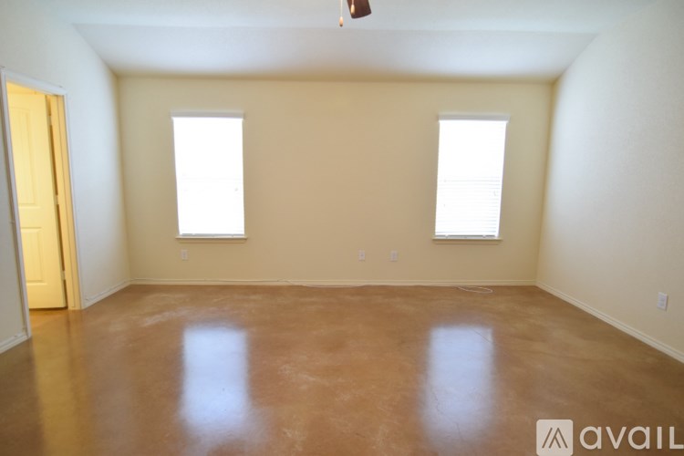 A room with brown floor and two windows.