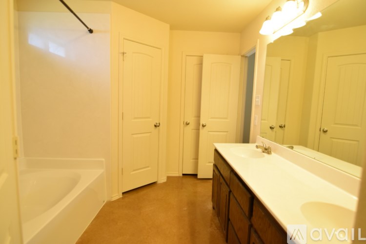 A bathroom with a tub, sink and mirror.