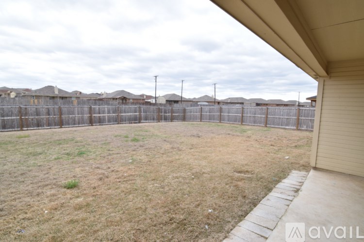 A backyard with a fence and a grassy area.