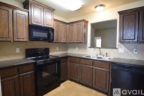 A kitchen with wooden cabinets and black appliances.