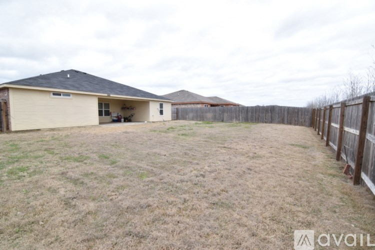 A backyard with a fence and a house in the background.